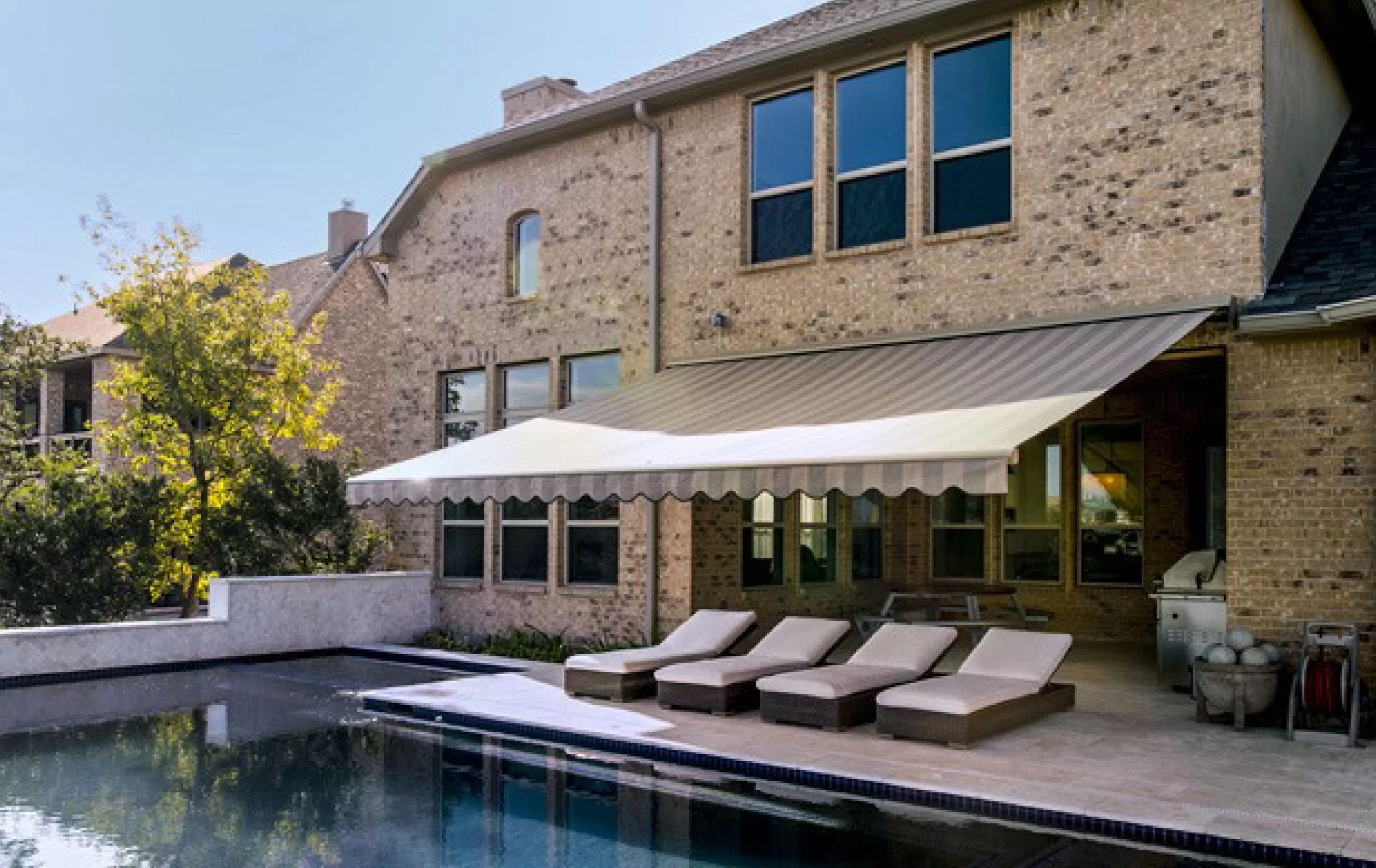 retractable awnings by sunesta on the back patio next to a pool